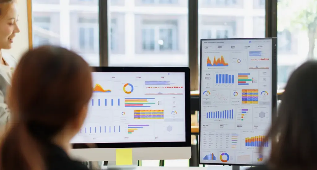 Equipa a analisar um dashboard de marketing de performance em dois monitores